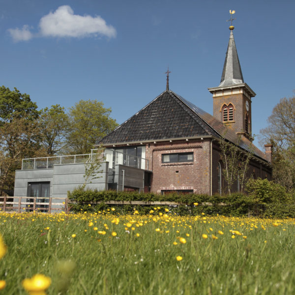 Huisje in de weide met kerk op de achtergrond