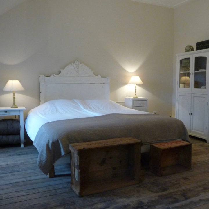 Een B&B kamer met tweepersoons bed, houten kisten naast het bed