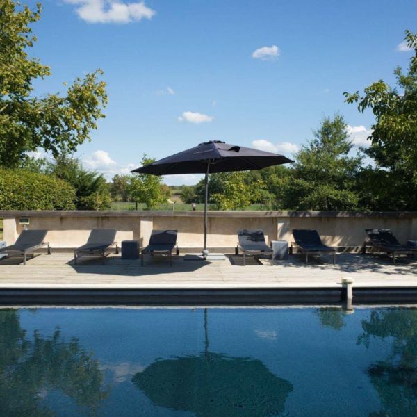 Zwembad met zwarte parasol en ligstoelen