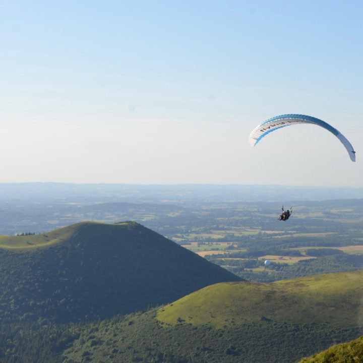 Groen heuvelland met een paraglider erboven