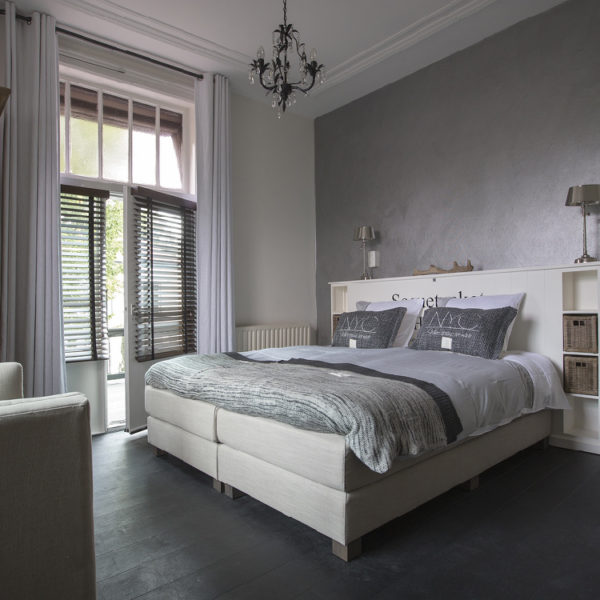 Een van de kamers van boutique hotel. Zachte grijs tinten, grote openslaande balkondeuren