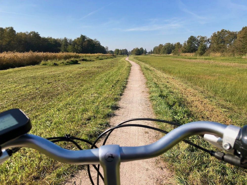 Een stuur van een fiets op een smal schelpen fietspad door nationaal park de weerribben-wieden