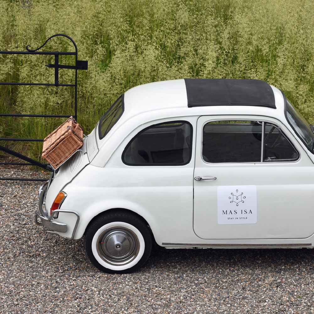 Fiat 500 in het wit, met een rieten koffertje achterop