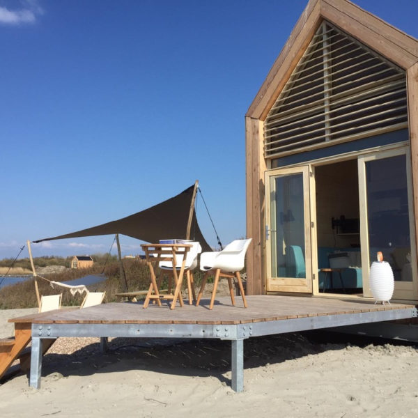 Duurzaam houten vakantiehuis met terras met witte designstoelen