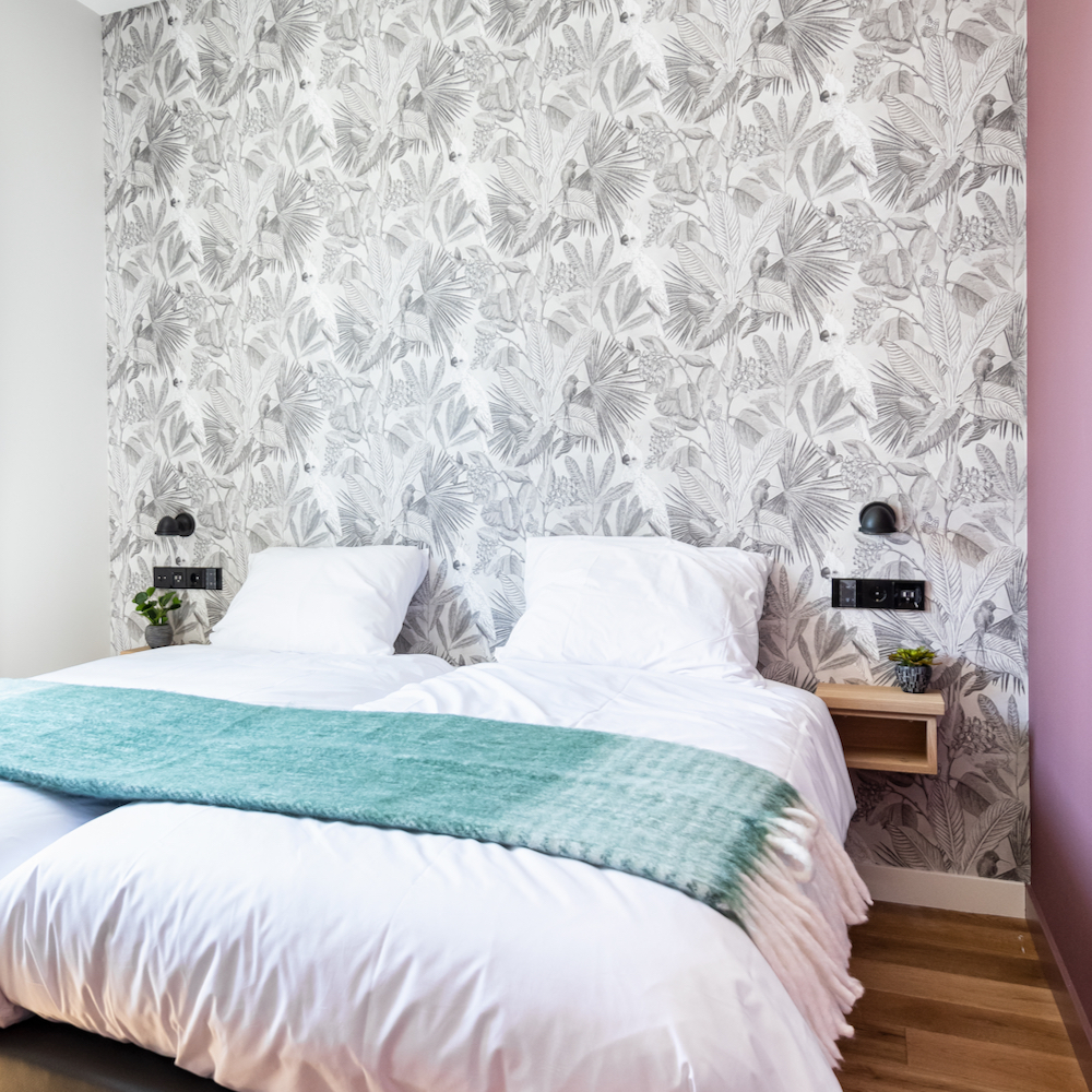 Slaapkamer in het appartement met bloemenbehang en roze wand