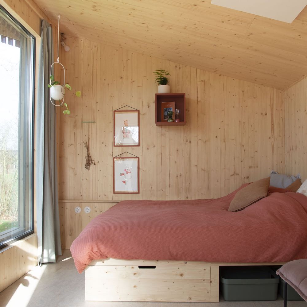 Tweepersoons bed voor groot raam in het tiny house