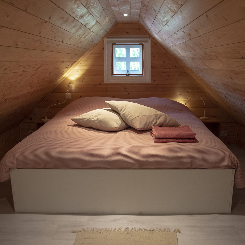Tweepersoons bed op de vide van het knusse huisje