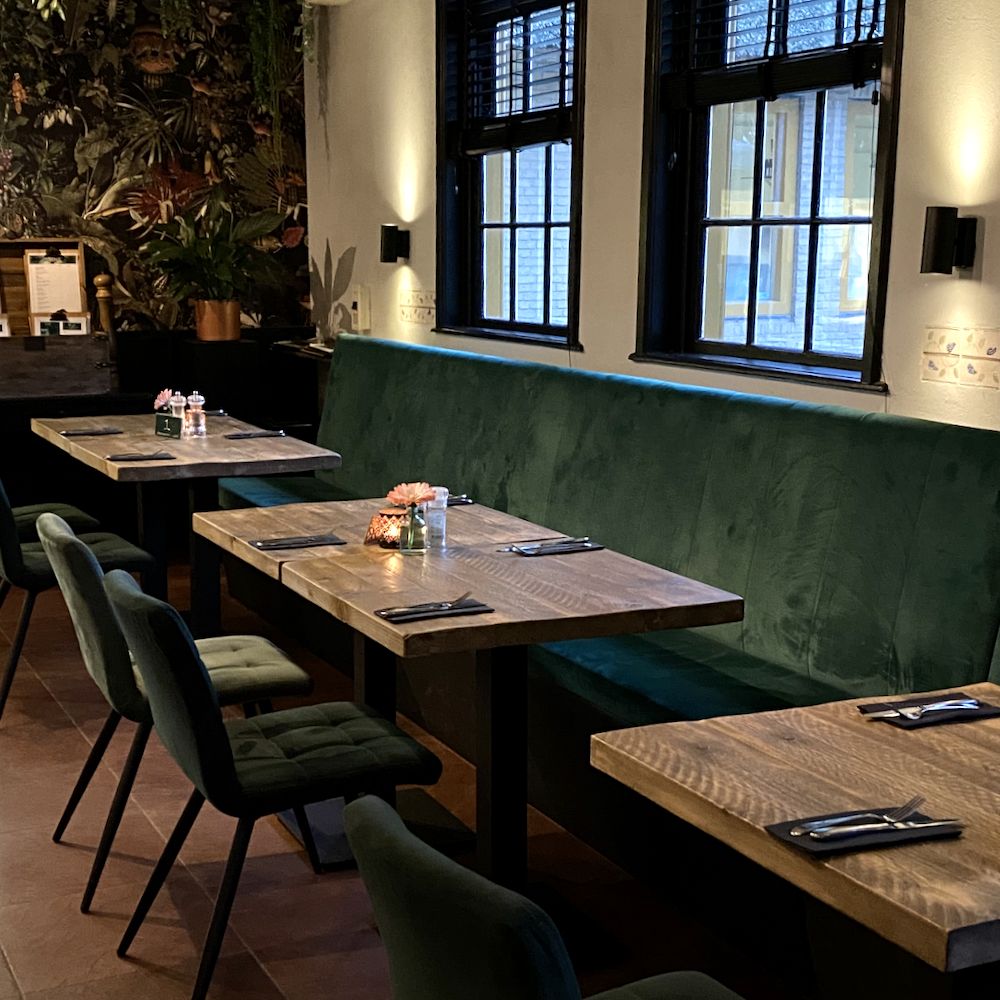 Tafels met groene fluwelen bank langs de wand